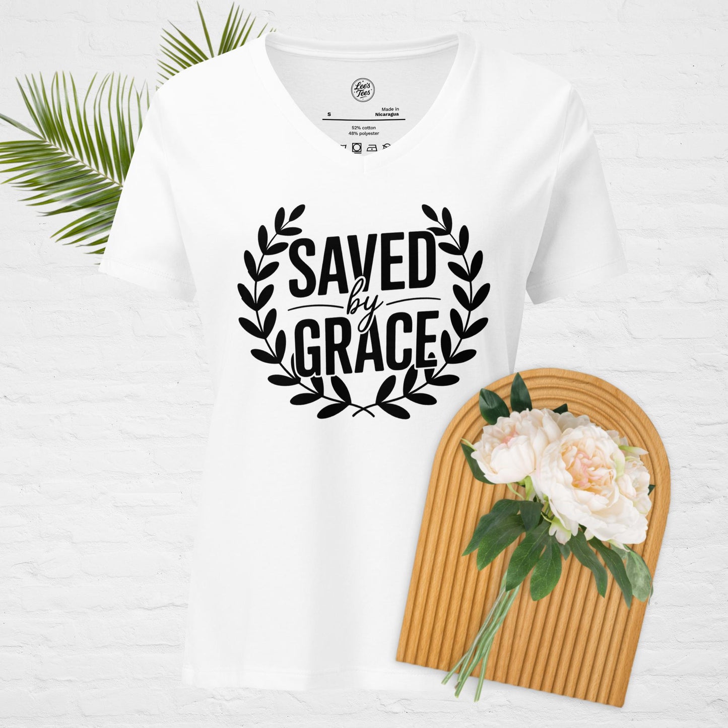 A white v-neck t-shirt with "Saved by Grace" in a wreath design.